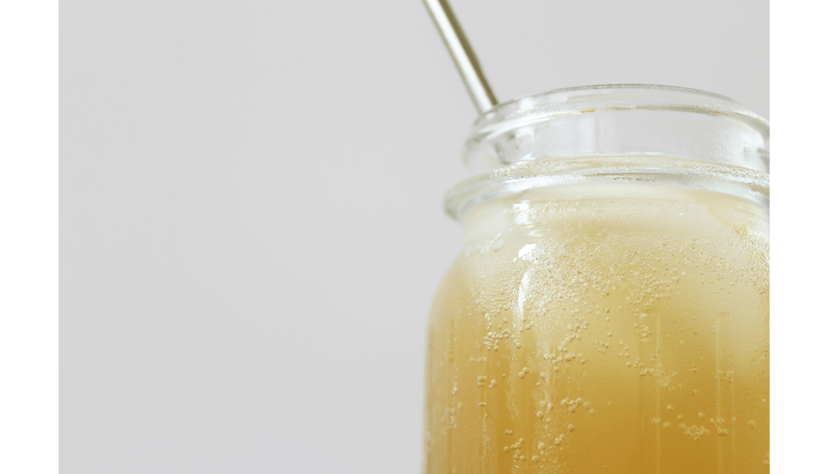A glass of fizzy kombucha with a metal straw