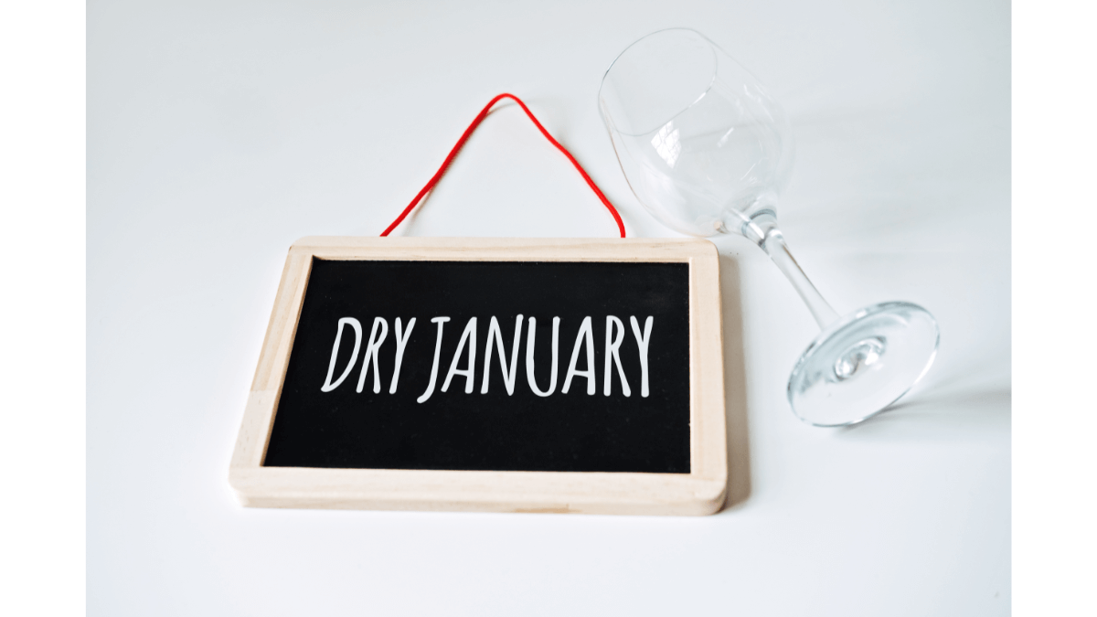 Dry January written on dry erase board next to a fallen wine glass